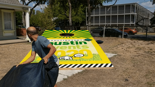 Weird Austin: Man throws a giant beanbag into a giant cornhole board.