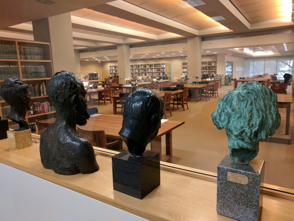 Spacious interior of the Harry Ransom Center showcasing four busts and unoccupied tables.