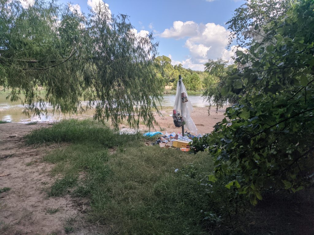 Section of the Colorado River obscured by trees and litter.