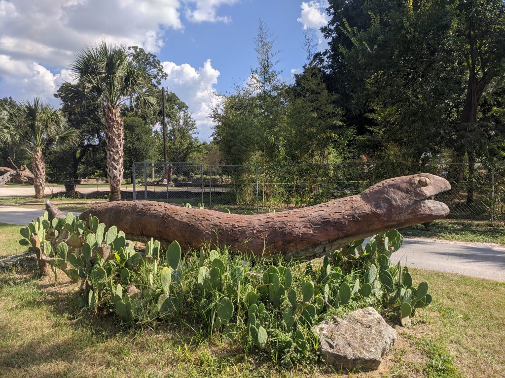 Weird Austin: A 12 foot long wooden snake in some cactus on the side of the road.