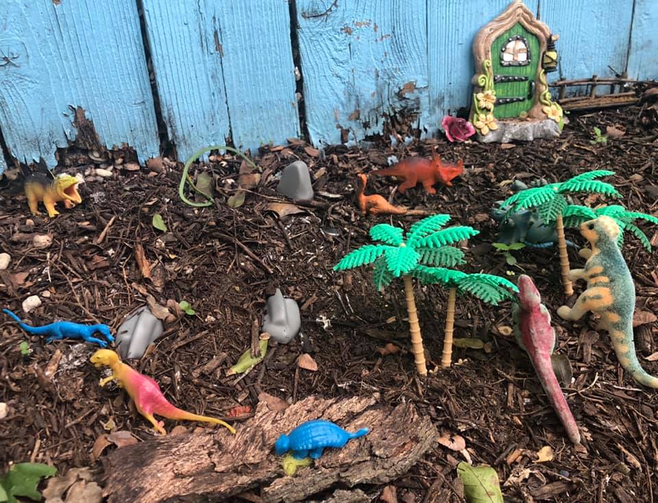 Miniature toy dinasaurs put near a wooden fence in Fairy Alley.