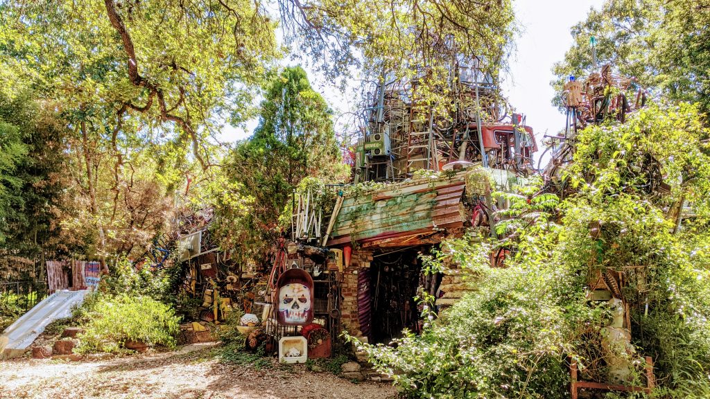 Exterior view of the Cathedral of Junk in Austin, surrounded by greenery on a sunny day.
