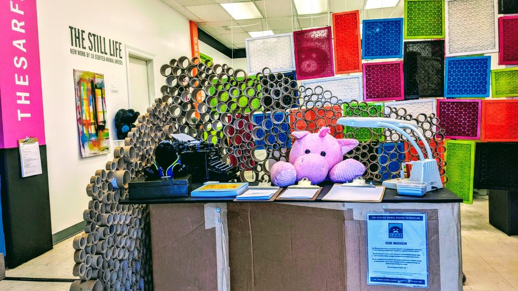 Reception desk at the Stuffed Animal Rescue Foundation, featuring a pink stuffed animal serving as a receptionist.